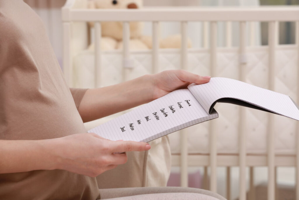 A woman reviewing unique baby names options on a notepad in front of a baby crib